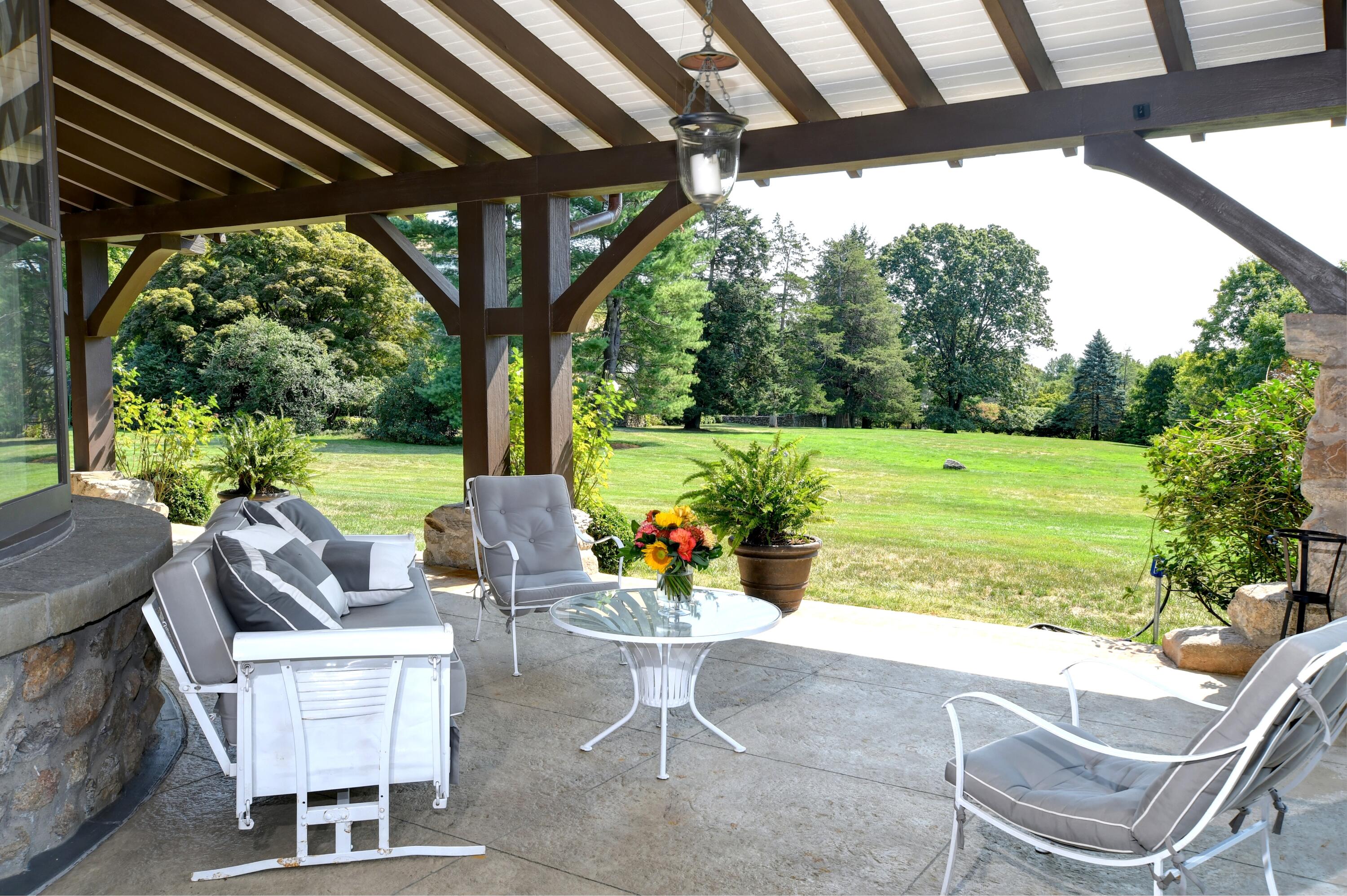 255 Brushy Ridge Road New Canaan, CT 06840 - Photo 5 of 40 a view of a patio with a table chairs and a backyard