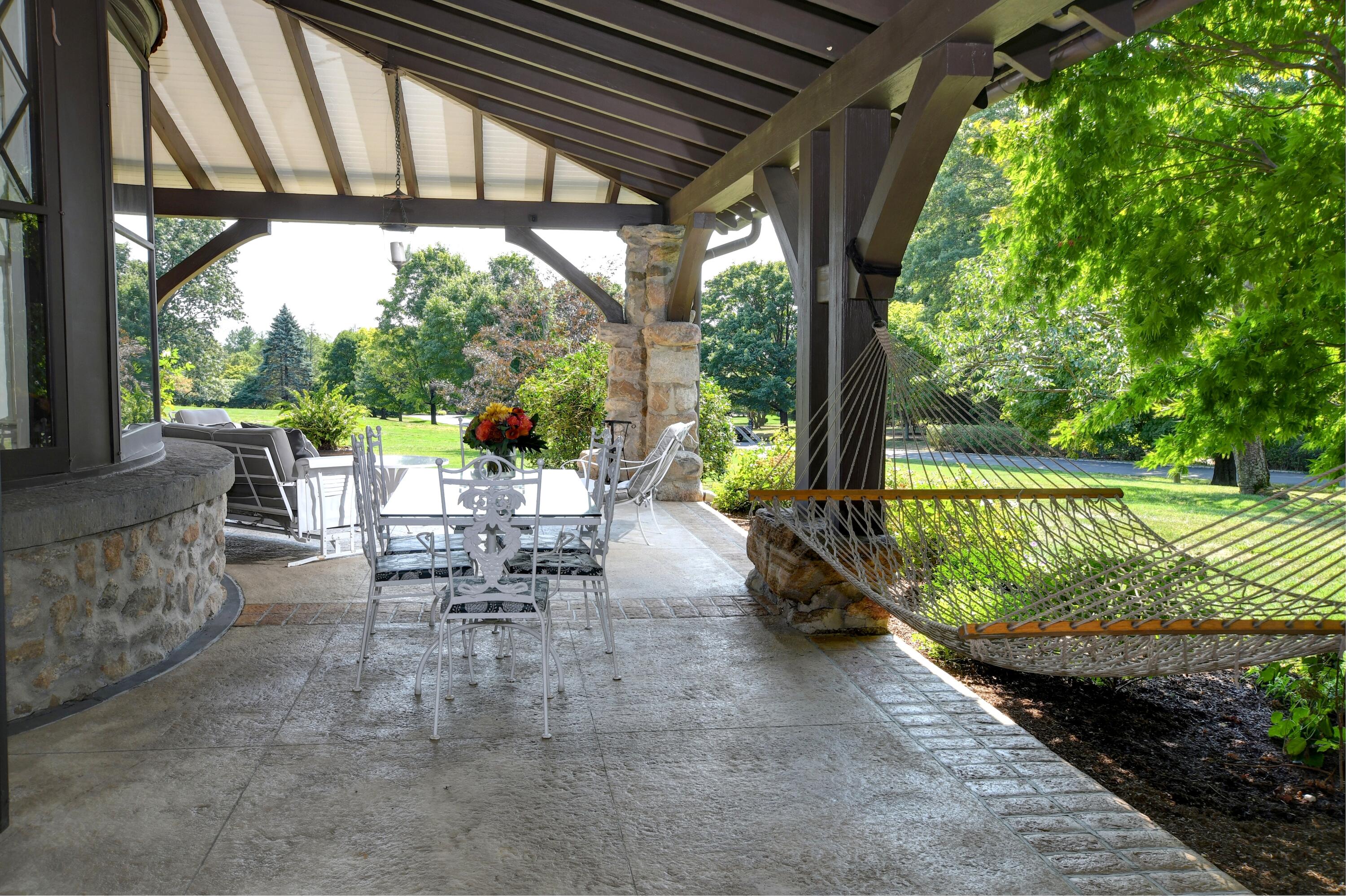 255 Brushy Ridge Road New Canaan, CT 06840 - Photo 9 of 40 a view of a patio with table and chairs potted plants with floor to ceiling window plants and trees