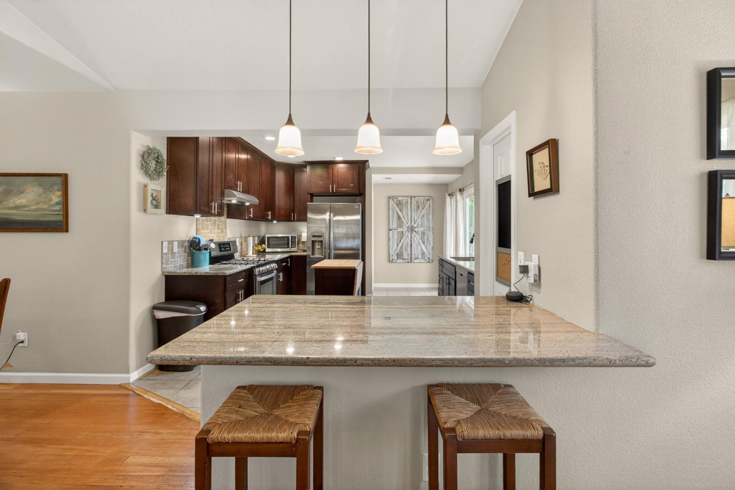 6332 Horseshoe Bar Road Loomis, CA 95650 - Photo 5 of 85 Kitchen featuring a granite countertop peninsula with pendant lighting, rich wood cabinetry, stainless steel appliances, and a tiled backsplash