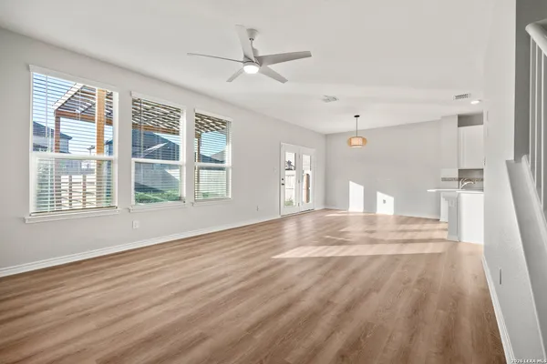 a view of empty room with wooden floor and fan