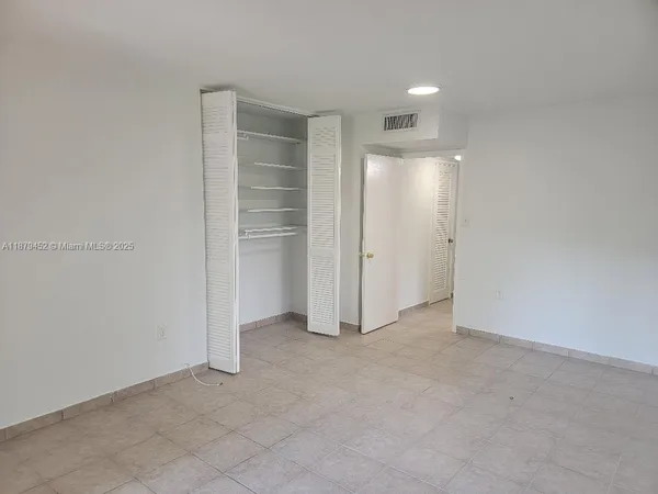an empty room with closet and windows