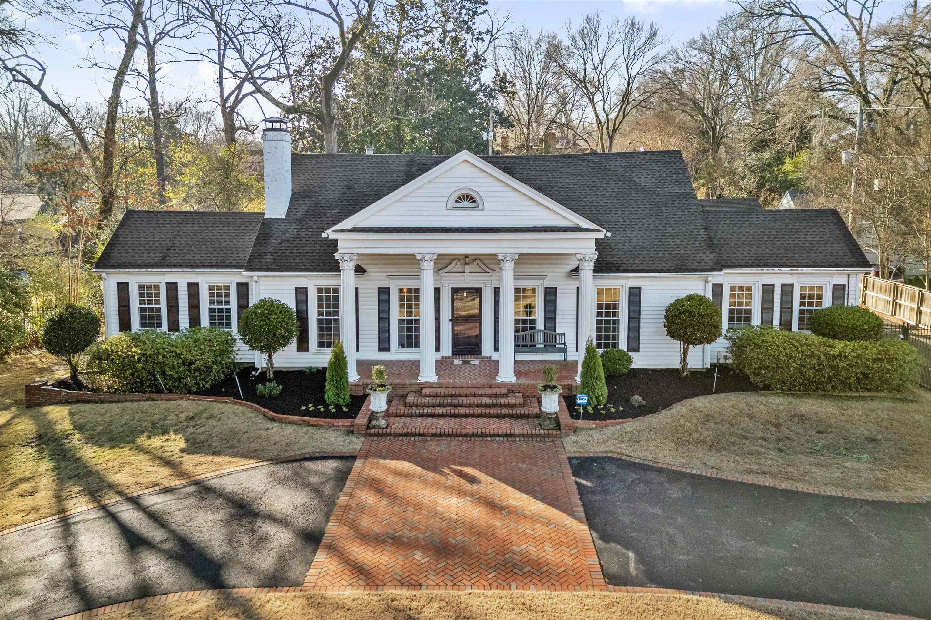 Neoclassical / greek revival house featuring covered porch, a chimney, and a shingled roof