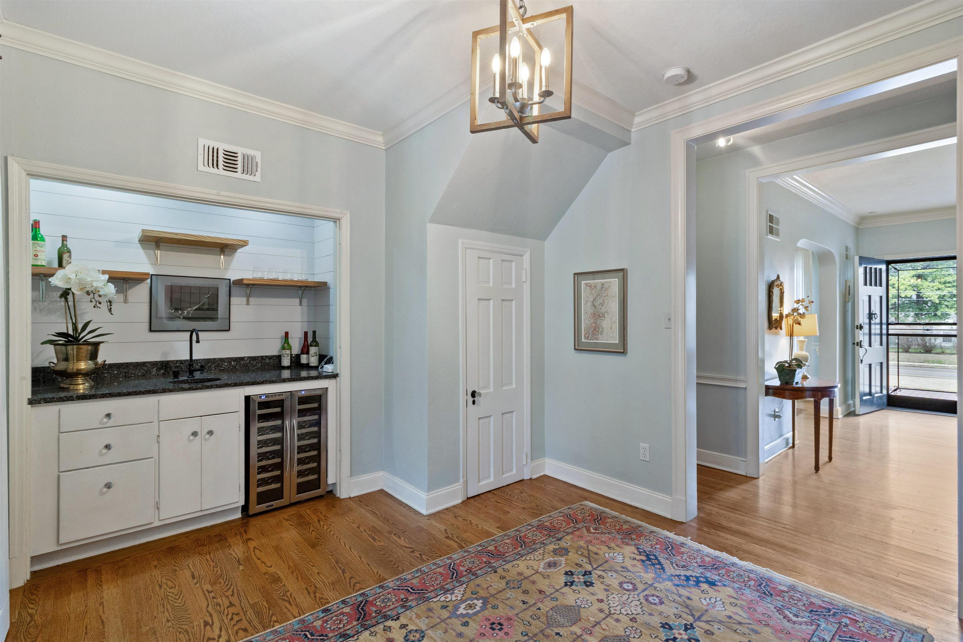 4009 Walnut Grove Road Memphis, TN 38117 - Photo 12 of 40 Indoor wet bar featuring wine cooler, ornamental molding, open shelves, dark stone countertops, and light wood finished floors