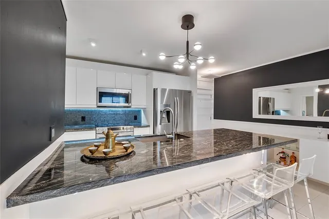 a kitchen with kitchen island granite countertop a sink a stove and cabinets
