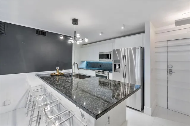 a kitchen with stainless steel appliances granite countertop a sink refrigerator and microwave