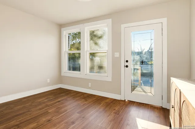 a view of an empty room with wooden floor and a window