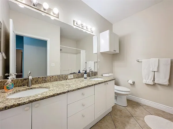 a bathroom with a granite countertop toilet sink and a mirror