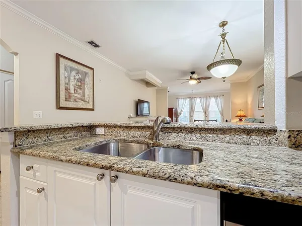 a kitchen with kitchen island granite countertop a sink a counter top space and cabinets