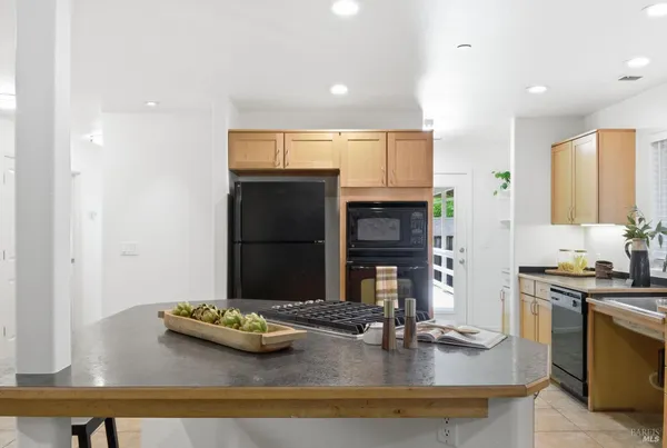 a kitchen with kitchen island granite countertop a sink and a stove top oven with wooden floor