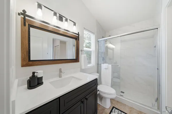 a bathroom with a granite countertop sink toilet a mirror and shower
