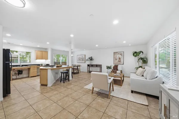 a living room with couches and kitchen view with wooden floor