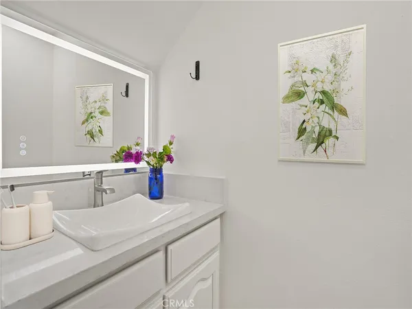 a bathroom with a sink a mirror and painting on the wall