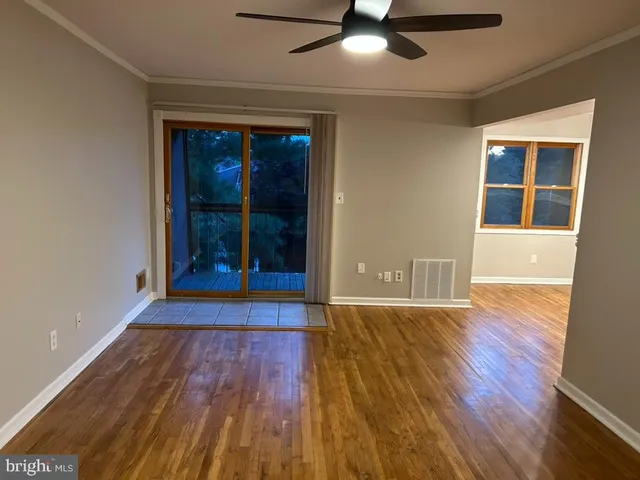 a view of an empty room with wooden floor and a window