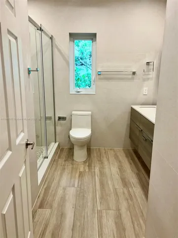 a bathroom with a sink a toilet a window and shower