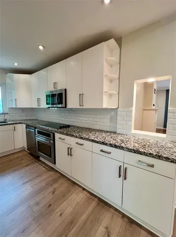 a kitchen with granite countertop white cabinets and white appliances