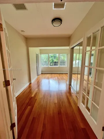 a view of empty room with wooden floor and fan