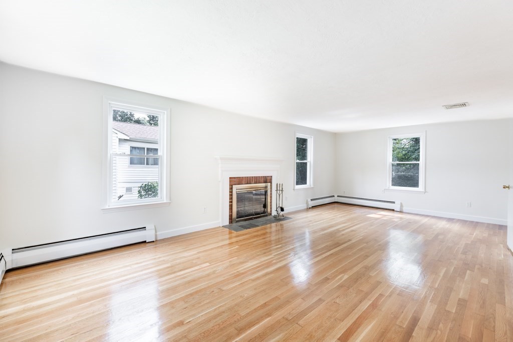 8 Michael Road Wakefield, MA 01880 - Photo 8 of 35 an empty room with wooden floor fireplace and windows