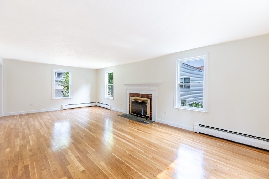 8 Michael Road Wakefield, MA 01880 - Photo 9 of 35 an empty room with windows fireplace and wooden floor