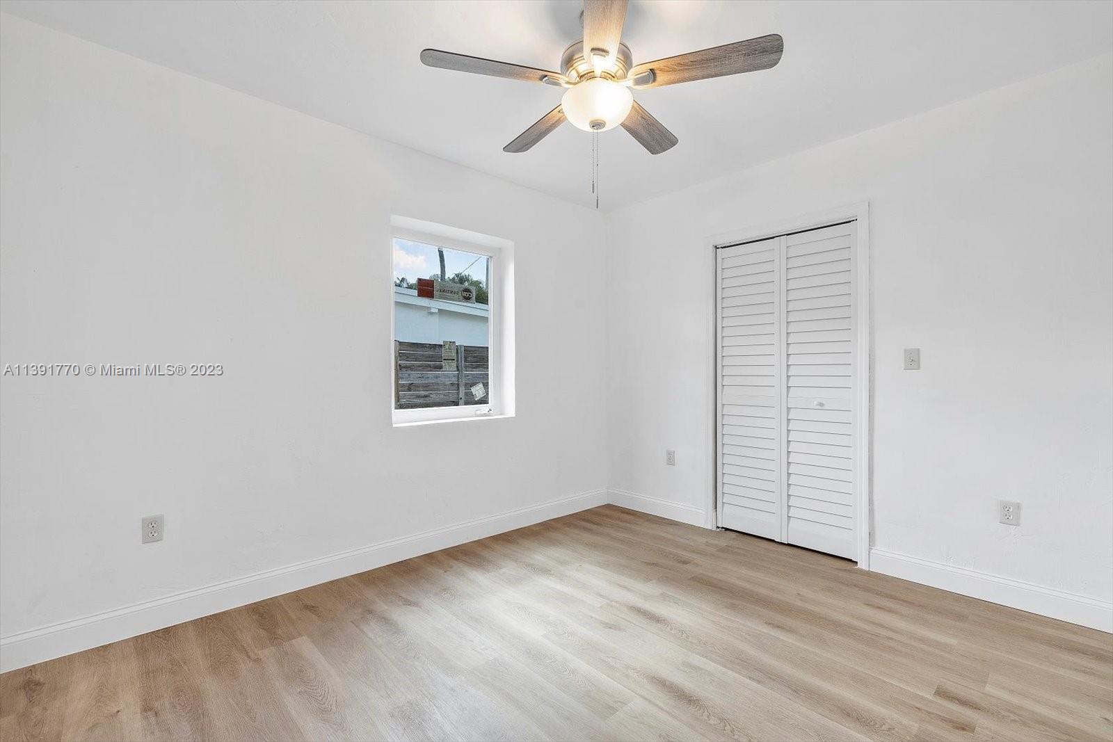 6110 Southwest 20th Street Miami, FL 33155 - Photo 21 of 29 an empty room with wooden floor chandelier fan and windows