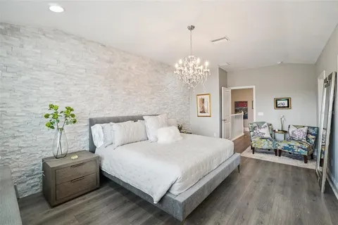 a large bed sitting in a bedroom next to a chandelier and a wooden floor