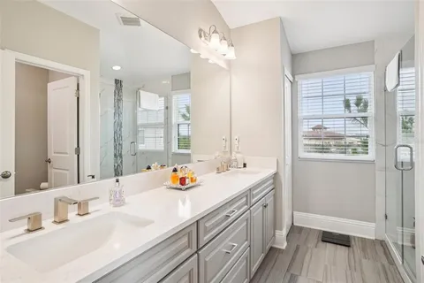 a en suite bathroom with a granite countertop shower a sink and a mirror