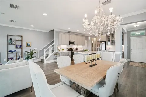 a dining room with kitchen island stainless steel appliances furniture dining table and wooden floor