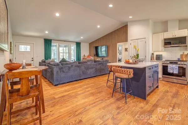 a living room with stainless steel appliances granite countertop furniture wooden floor and a view of kitchen