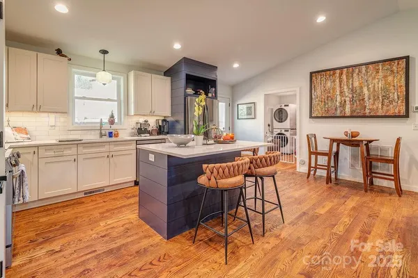 a room with stainless steel appliances kitchen island granite countertop a sink and cabinets