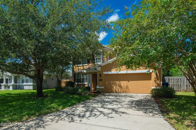a front view of a house with a garden and tree