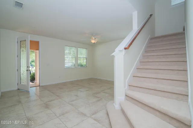 a view of an empty room with stairs and a window