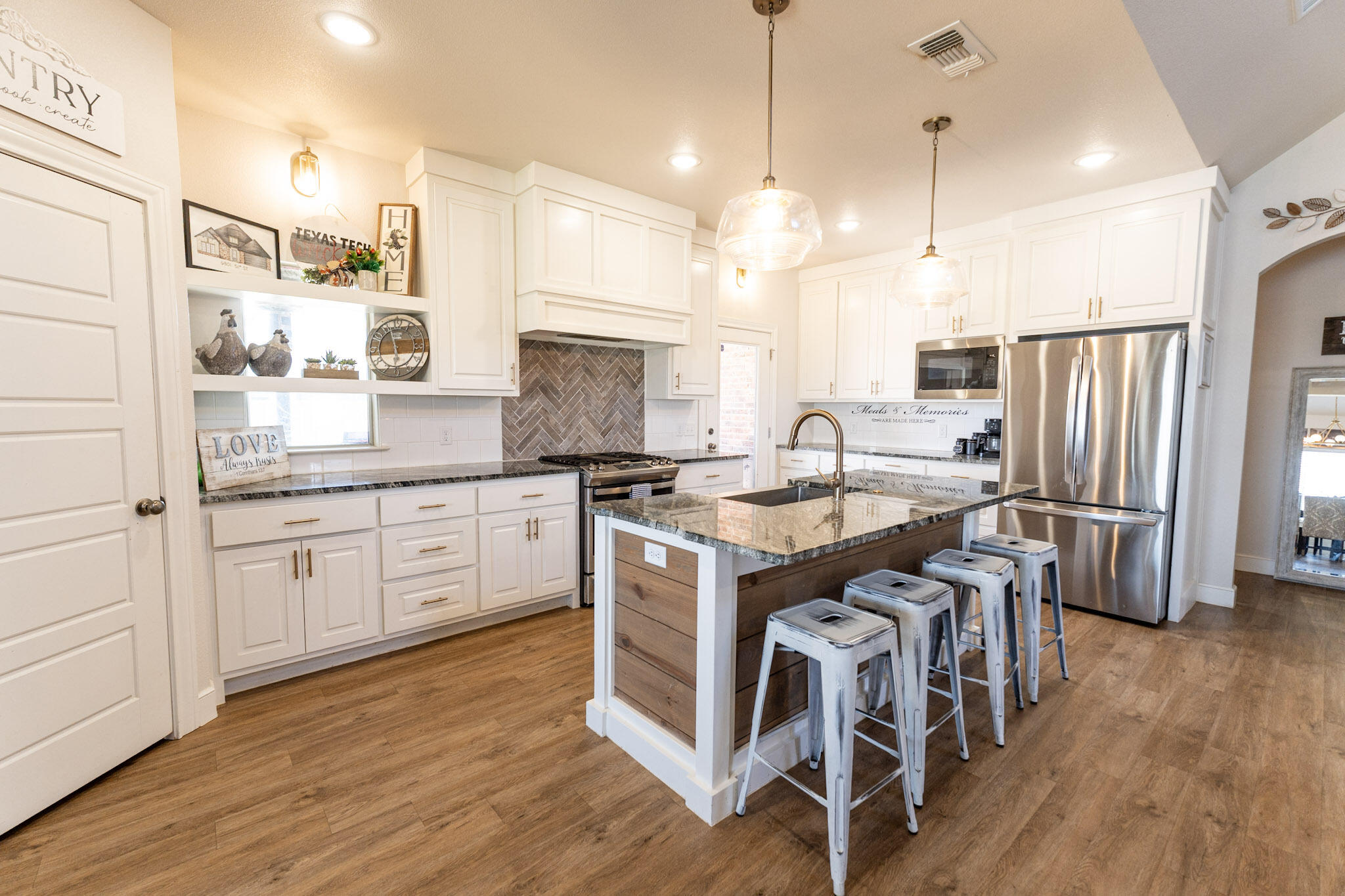 6801 51st Street Lubbock, TX 79407 - Photo 4 of 19 a kitchen with stainless steel appliances granite countertop a table chairs stove and wooden floor