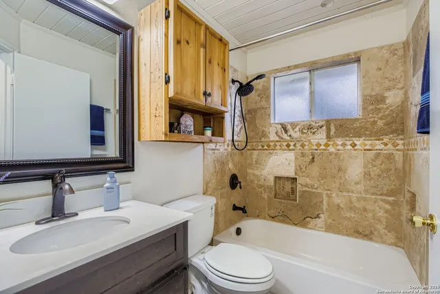 a bathroom with a bathtub shower sink mirror vanity and toilet