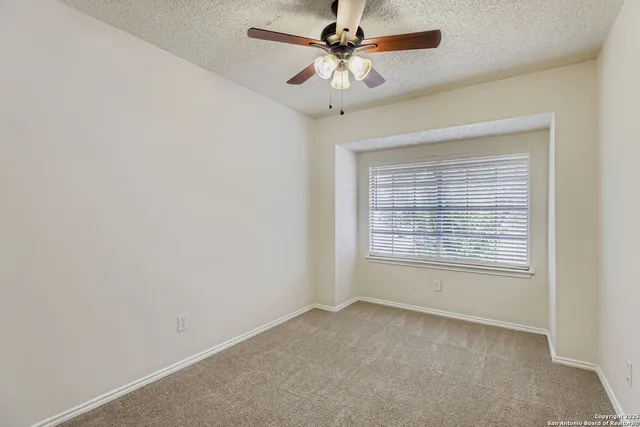 an empty room with a window and a fan
