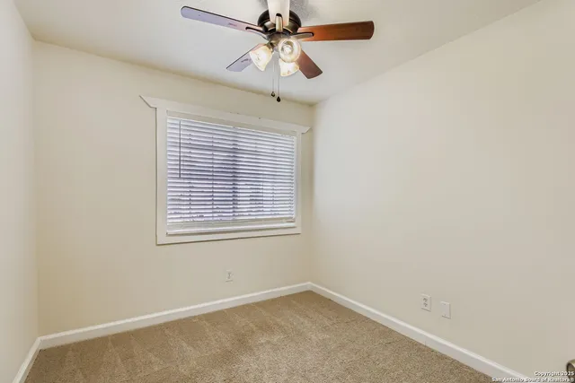 an empty room with a window and a fan