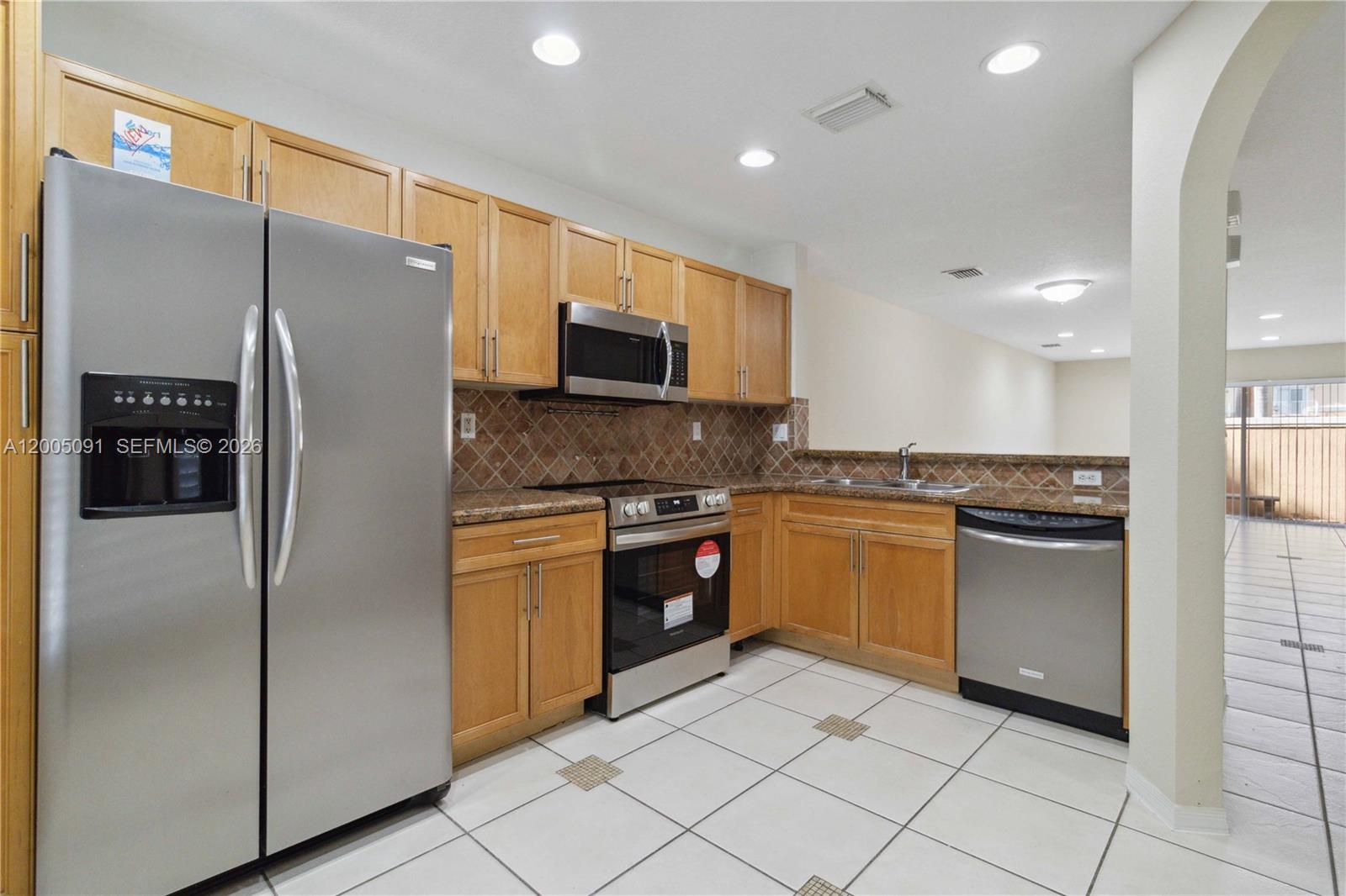 3079 Southwest 129th Way, Unit 159 Miramar, FL 33027 - Photo 13 of 44 a kitchen with stainless steel appliances granite countertop a refrigerator and a stove top oven