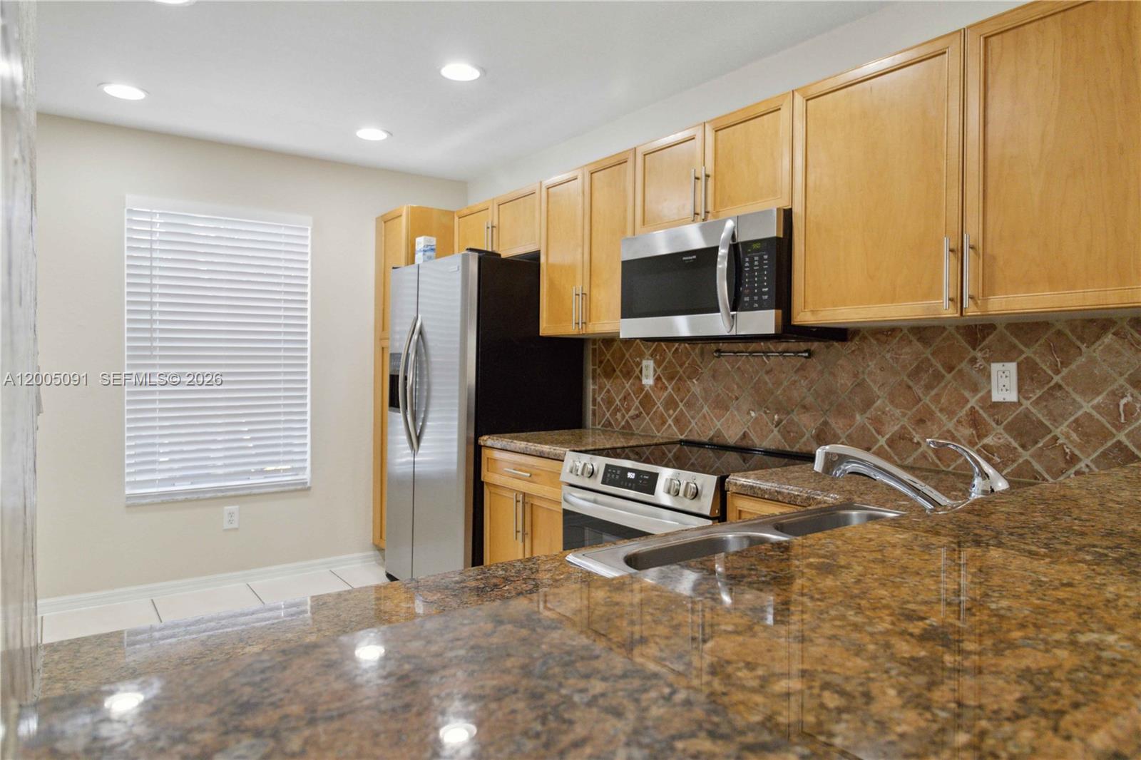 3079 Southwest 129th Way, Unit 159 Miramar, FL 33027 - Photo 14 of 44 a kitchen with stainless steel appliances granite countertop a stove a sink and a microwave
