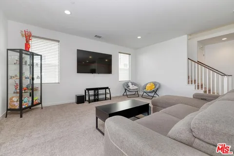 a living room with furniture and a large window with kitchen view