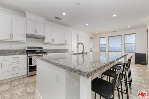 a kitchen with stainless steel appliances kitchen island granite countertop a dining table chairs and a refrigerator