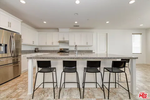 a kitchen with stainless steel appliances granite countertop a table chairs sink refrigerator and microwave