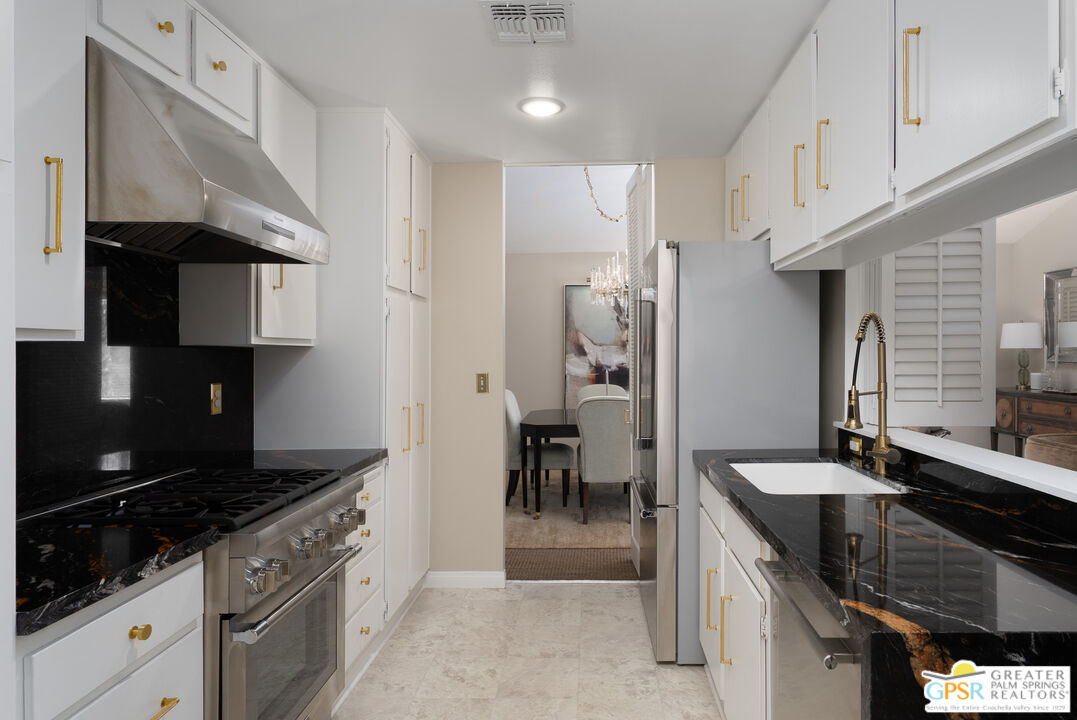 566 North Sunset Way Palm Springs, CA 92262 - Photo 9 of 39 a kitchen with stainless steel appliances granite countertop a sink stove and cabinets