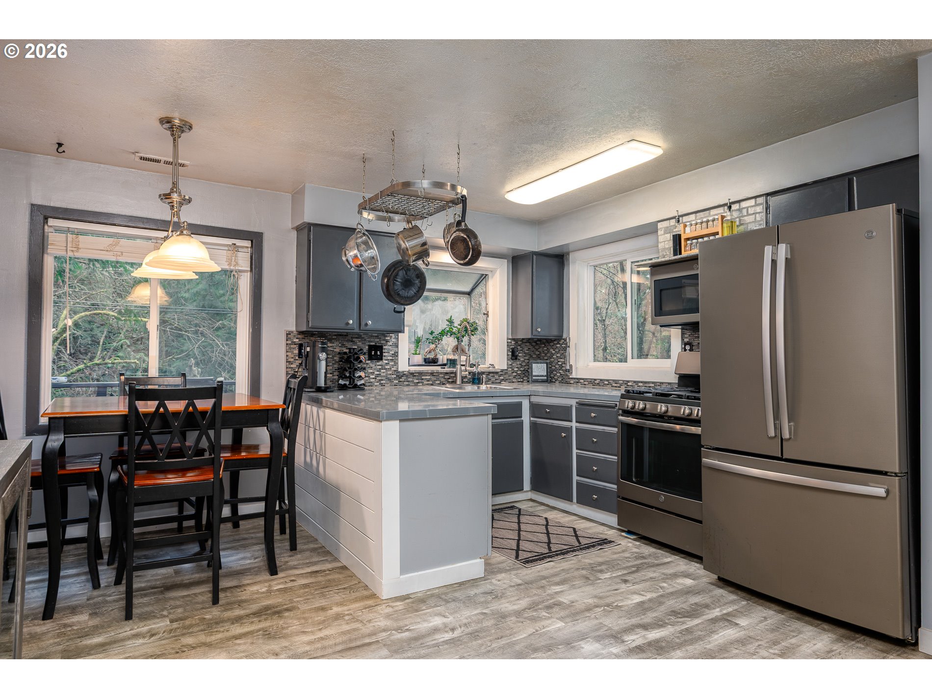 2685 Southwest 89th Avenue Portland, OR 97225 - Photo 15 of 37 a kitchen with stainless steel appliances kitchen island granite countertop a table chairs stove and refrigerator