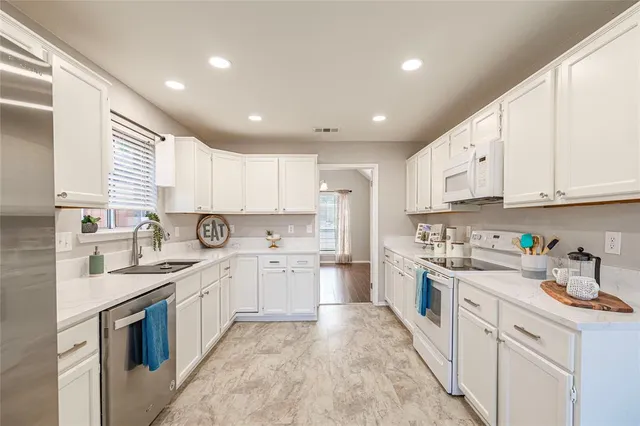 a kitchen with white cabinets appliances and a sink