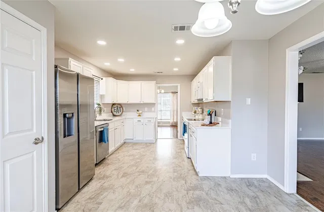 a view of a kitchen with a sink and dishwasher a refrigerator with white cabinets