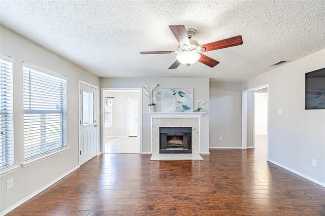 an empty room with wooden floor a ceiling fan and a fireplace