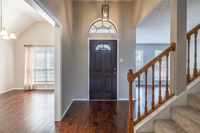 a view of a hallway with wooden floor stairs and a chandelier