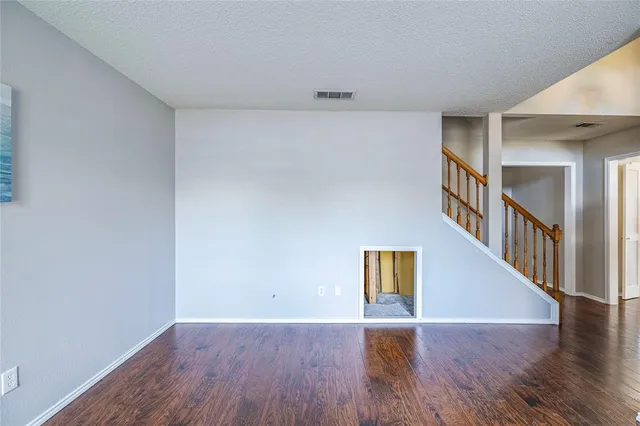 a view of an empty room with wooden floor and stairs