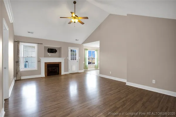 a view of an empty room with a fireplace and wooden floor
