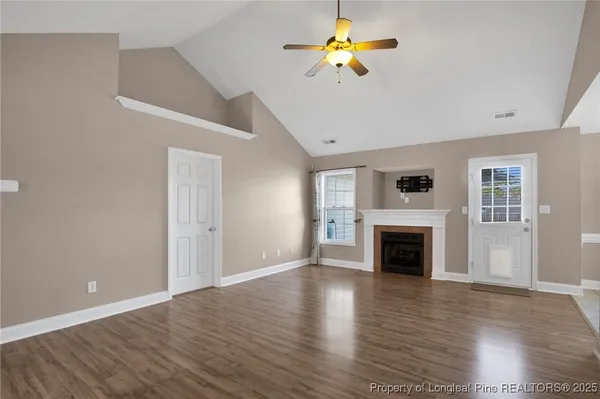 a view of an empty room with window and wooden floor
