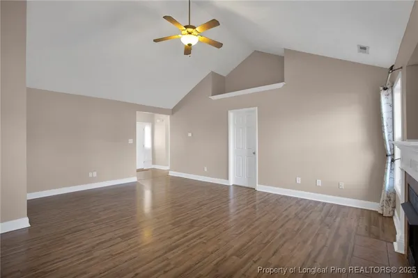 a view of an empty room with window and wooden floor
