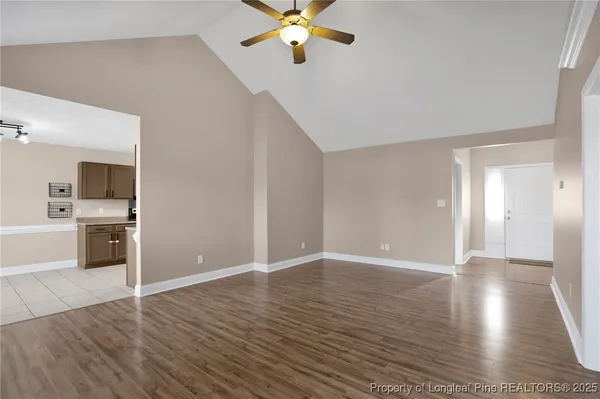 a view of an empty room with window and wooden floor